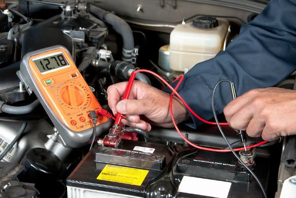 Mechanic using test meter to evaluate a car's battery.